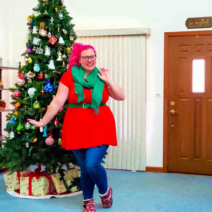 Chrissy in front of a Christmas tree wearing red and green