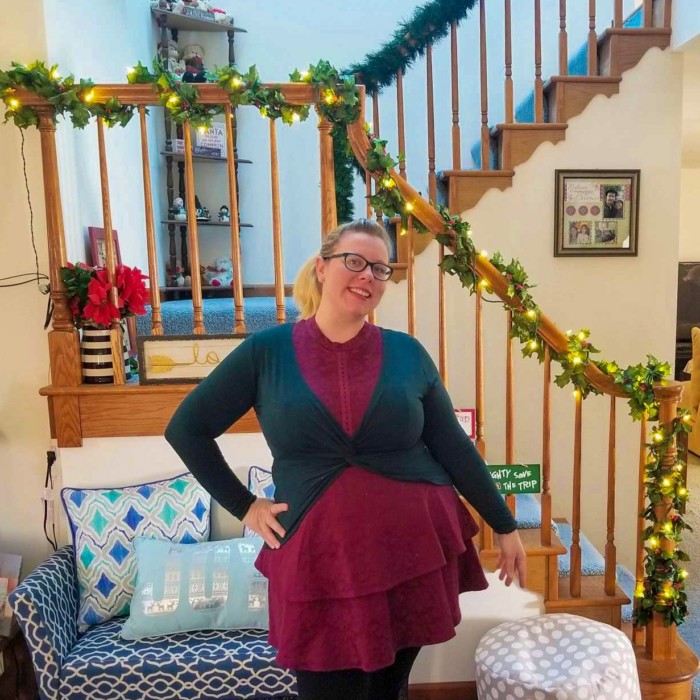 Chrissy wearing maroon and dark green in front of pre-lit garland